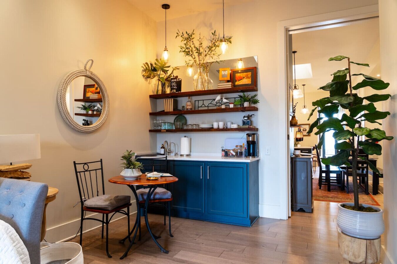 Une cuisine de taille réduite avec des meubles bleus, une table de salle à manger ronde et un luminaire suspendu.