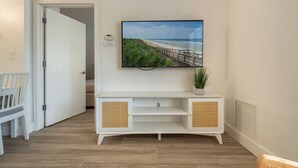 A hallway with a white console table, a potted plant, and a framed picture of a beach.