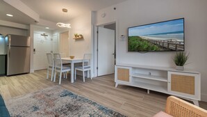 A modern kitchen with a built-in refrigerator, white cabinetry, and a dining area with a table and chairs.