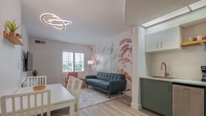 A modern living room with a sofa, dining table, and kitchen area.