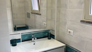 Un baño moderno con un lavamanos blanco, un espejo y una bañera.