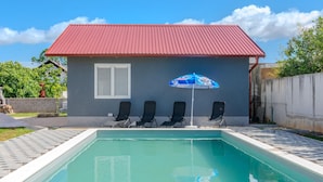 A swimming pool with four lounge chairs and a blue umbrella. - Nice home in Privlaka (Privlaka)