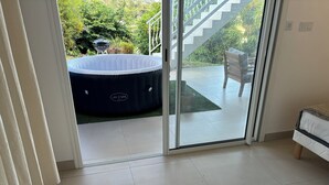 A room with a sliding glass door leading to a patio with a hot tub and outdoor furniture. - Noola t4 au Robert Vive L'aventure en Famille et Entre Amis (Le Robert)