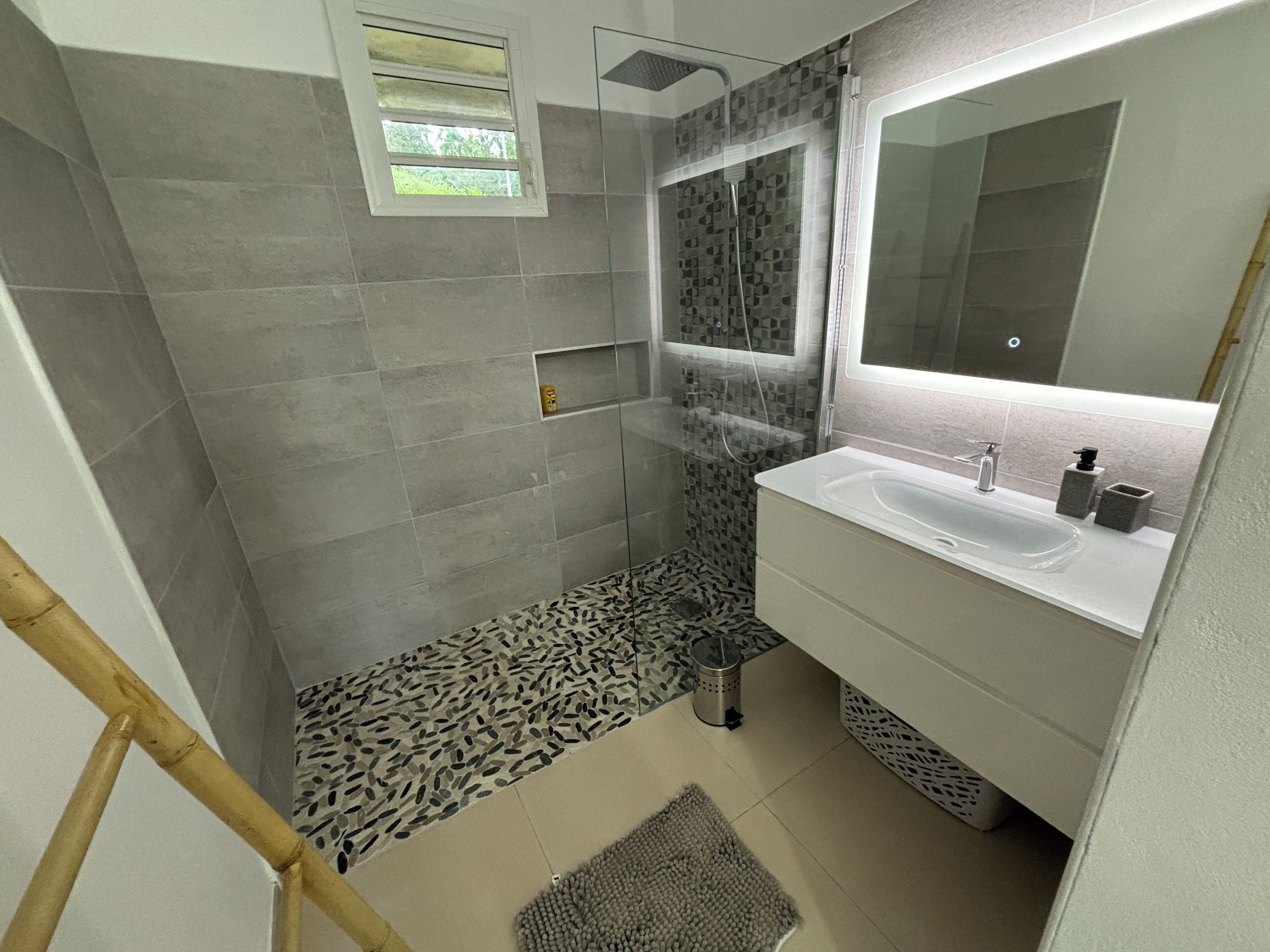 Une salle de bain avec une douche, un lavabo et un miroir.
