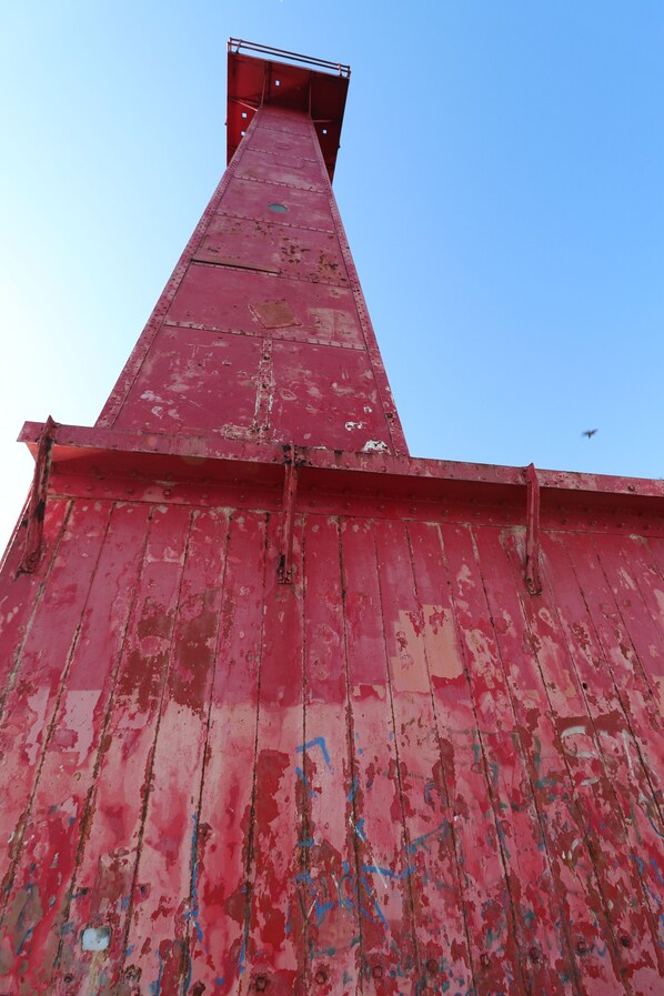 Una estructura metálica alta de color rojo con una parte superior puntiaguda y una base plana.