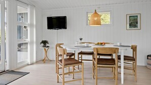 Un coin repas avec une table ronde, des chaises, un téléviseur et une fenêtre donnant sur un beau paysage.
