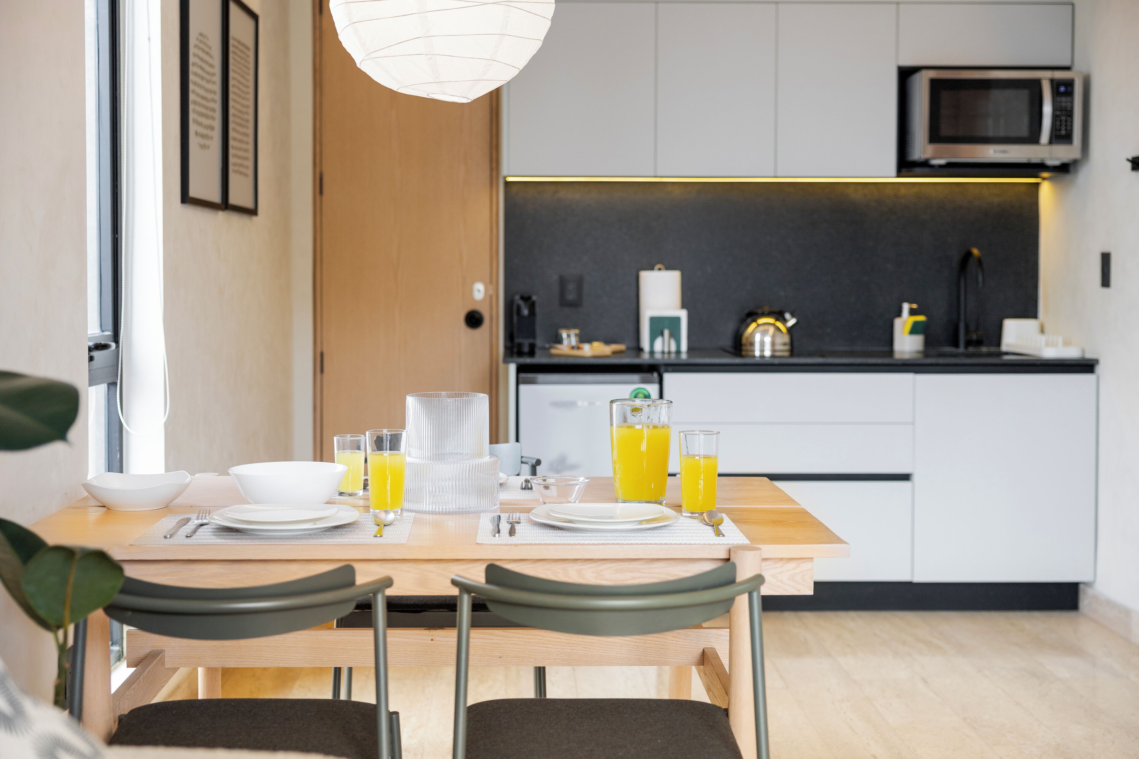 Une cuisine moderne équipée d’une table à manger pour deux personnes, d’un four à micro-ondes et d’une machine à café.