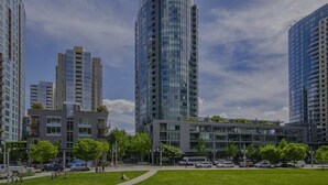 A modern urban area with high-rise buildings, a central plaza with greenery, and a clear sky. - Luxury high rise condo with river and mountain views, walk to OHSU (Portland)