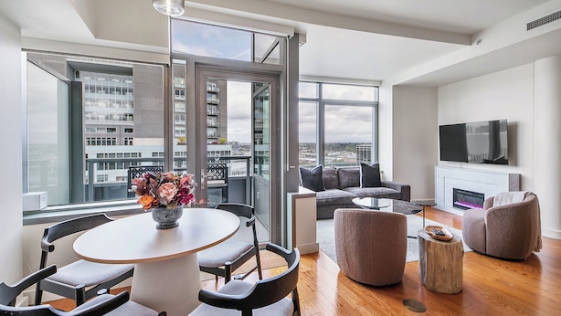 A modern living room with a round table, sofas, and a TV. - Luxury high rise condo with river and mountain views, walk to OHSU (Portland)