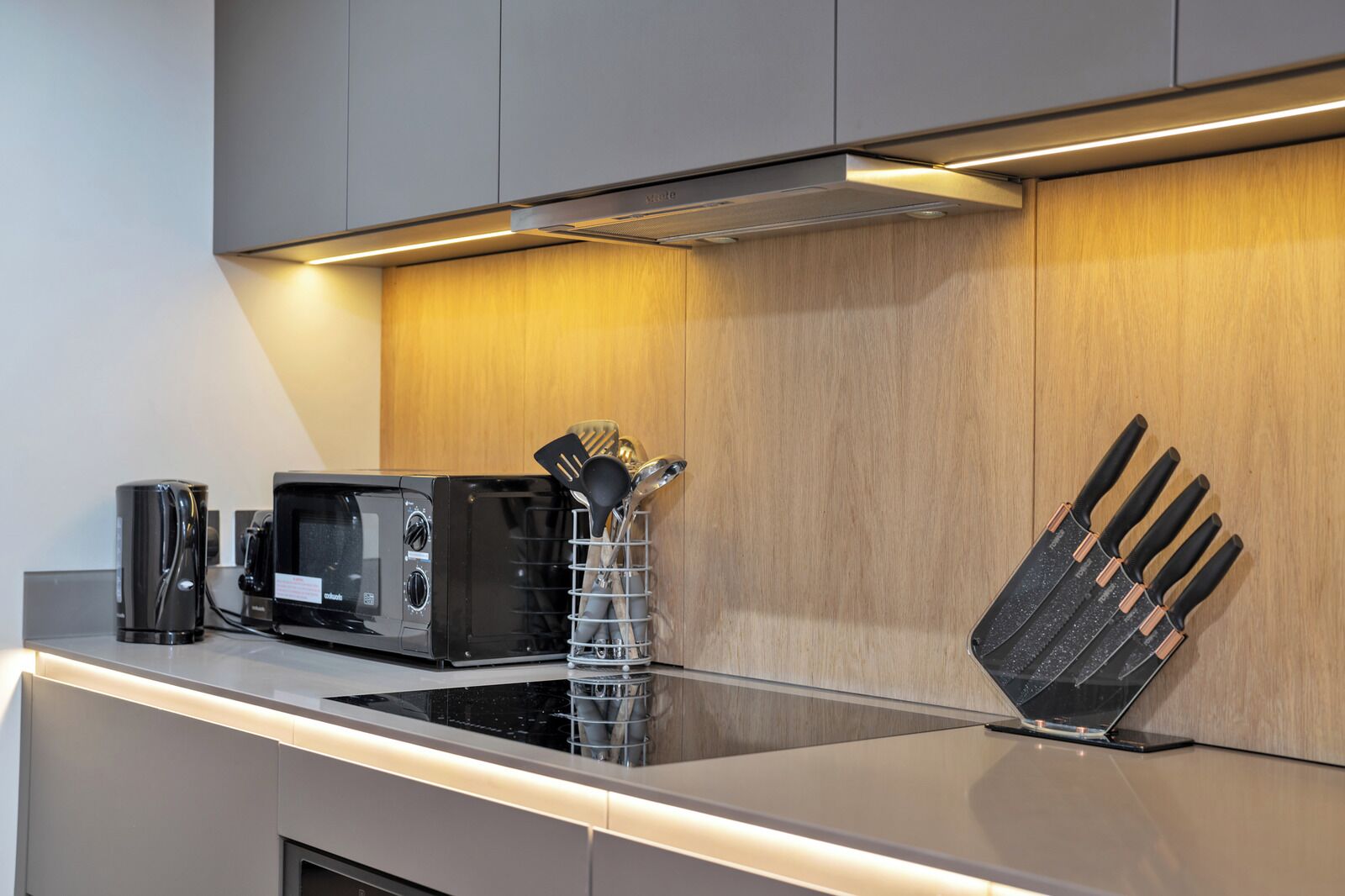 A modern kitchen with a microwave, coffee maker, and knife block on the counter.