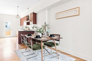 A modern kitchen with wooden cabinets, a dining table set for four, and a large window. - 3 LEVEL LUX Townhome! Near MetLife NYC EWR PATH, 4Bed/3Bath! (Jersey City)