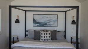 Une chambre à coucher avec un lit à baldaquin, un ventilateur de plafond et un tableau accroché au mur.