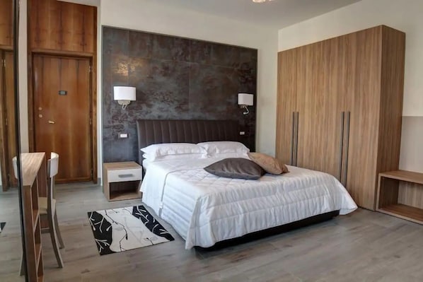 A bedroom with a bed, bedside tables, a wardrobe, and a nightstand.