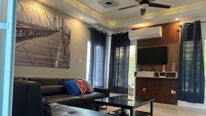 A modern living room with a sofa, a coffee table, and a TV mounted on the wall. - Elegant Villa, 7 Beds, Sleep 10. Beach access, Private pool, Bavaro Punta Cana (Punta Cana)