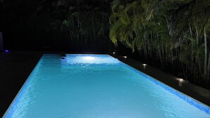 A swimming pool at night with illuminated edges, surrounded by palm trees. - Elegant Villa, 7 Beds, Sleep 10. Beach access, Private pool, Bavaro Punta Cana (Punta Cana)