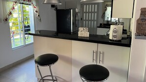 A kitchen with two bar stools, a refrigerator, and a sink. - Elegant Villa, 7 Beds, Sleep 10. Beach access, Private pool, Bavaro Punta Cana (Punta Cana)