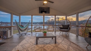 A spacious patio with a hammock, wicker chairs, and a view of the landscape. - Lakefront Getaway: Fire Pit ~ Dock ~ Games ~ Family & Pet Friendly (Waterloo)