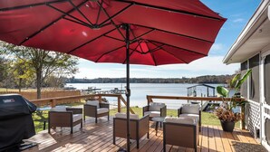 A deck with outdoor furniture, a red umbrella, and a view of a lake. - Lakefront Getaway: Fire Pit ~ Dock ~ Games ~ Family & Pet Friendly (Waterloo)