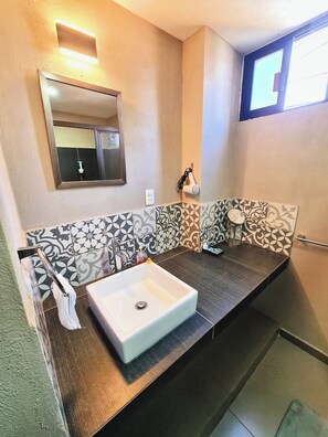 Bathroom features a large sink, shower area with glass door, and a towel rack.