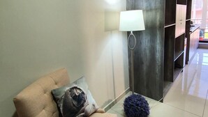 A modern living room with a beige armchair, a floor lamp, and a dark rug.