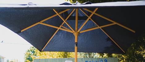 An outdoor seating area with a table and chairs, an umbrella, and a painted wall with a sun and waves design.
