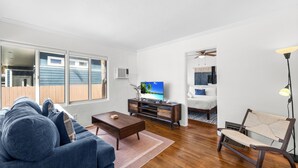 A living room with a blue sofa, wooden coffee table, and a TV on a wooden cabinet. - NEW Private Ocean Beach Home with Yard and Parking (San Diego)