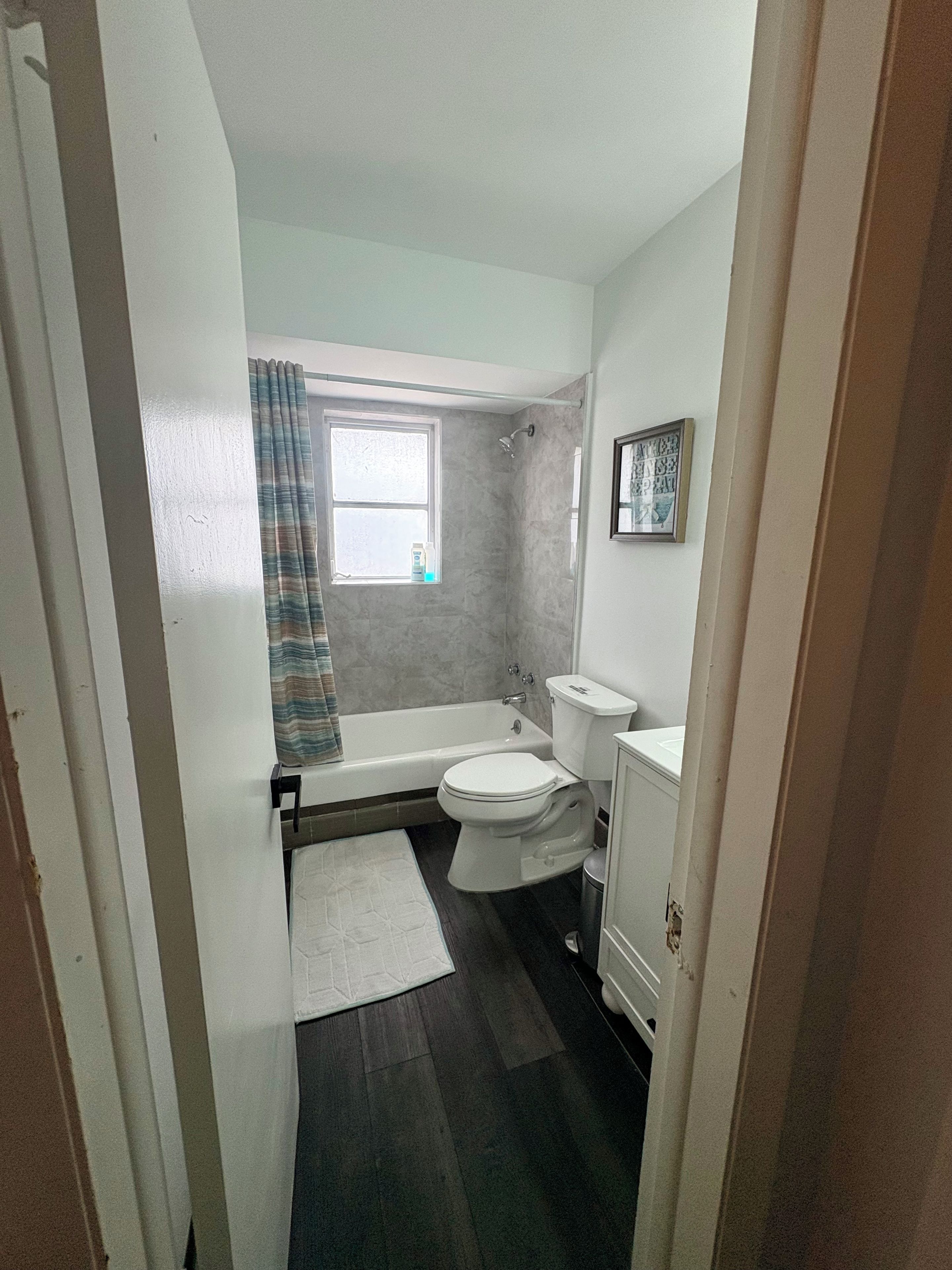 Un bagno con vasca, servizi igienici e una finestra con tende.