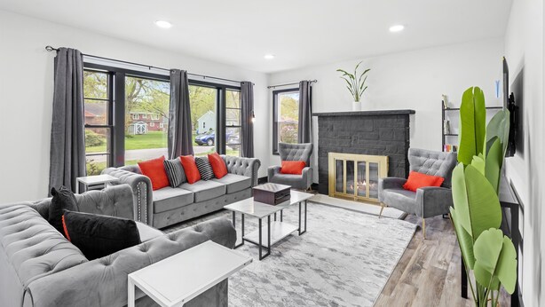 Una sala moderna con un sofá gris, una chimenea y ventanas amplias.