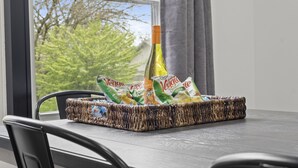Una cesta de mimbre sobre una mesa con una botella y paquetes de snacks Veggie.