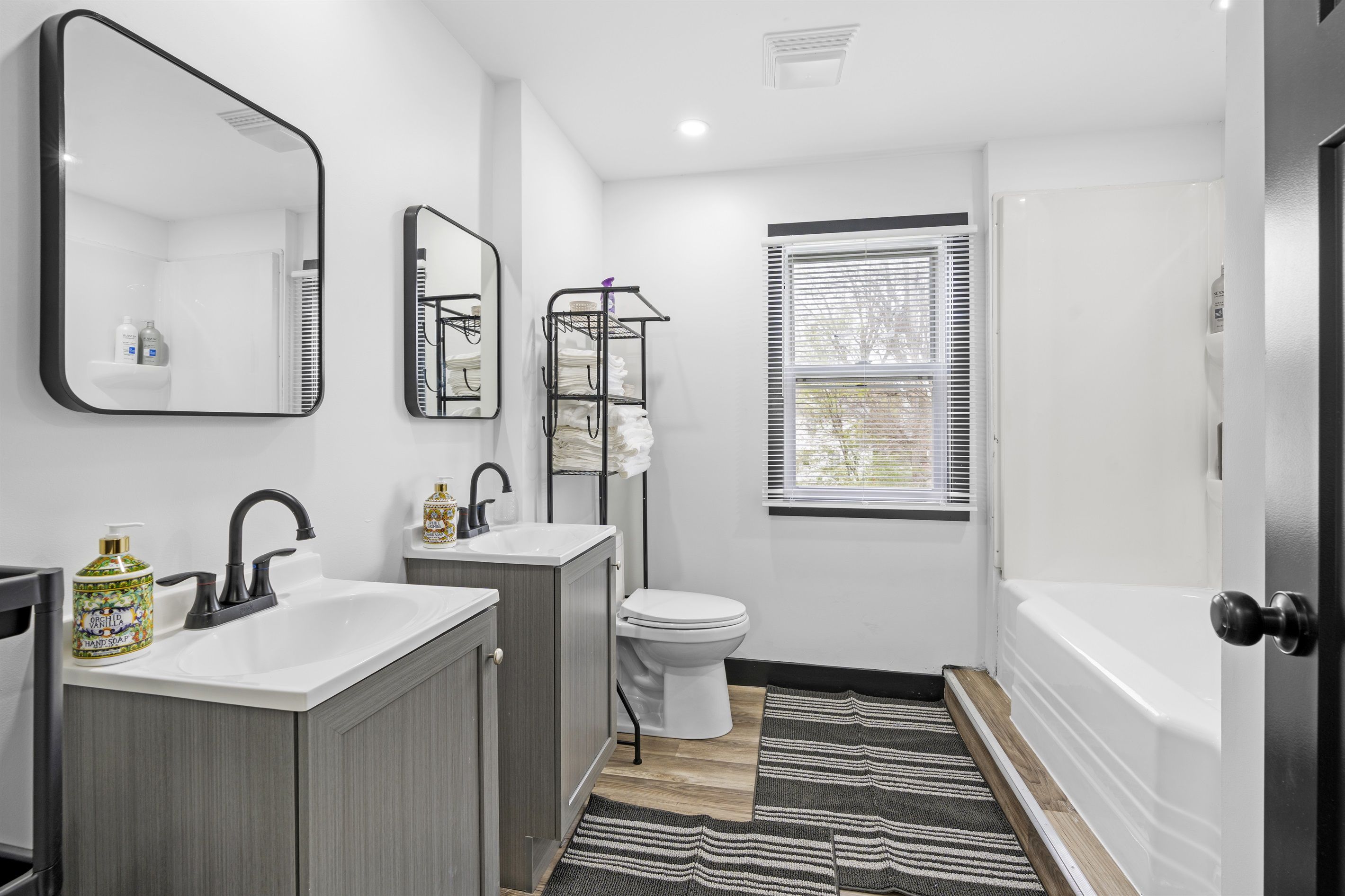 A modern bathroom with a vanity, sink, toilet, and bathtub.