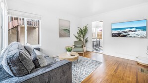 Un salon moderne avec un canapé gris, une table basse ronde et une vue sur l’océan par une grande fenêtre.