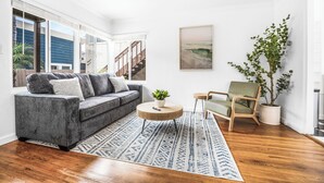 Un salon moderne avec un canapé gris, une table basse ronde, un tapis à motifs bleus et un plancher en bois.