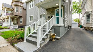 A two-story house with a stone facade, white railings, and a green door. - Sumner Park Residence (Rochester)