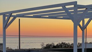 Eine weiße Pergola mit Blick auf das Meer bei Sonnenuntergang.