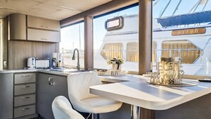 Une cuisine moderne avec un coin bar, des meubles blancs et une vue sur l’extérieur du bateau.