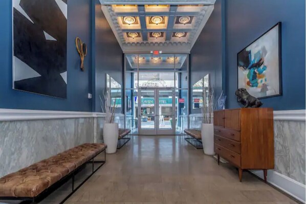 Enter a stylish lobby with a marble floor, a bench, and a dresser.