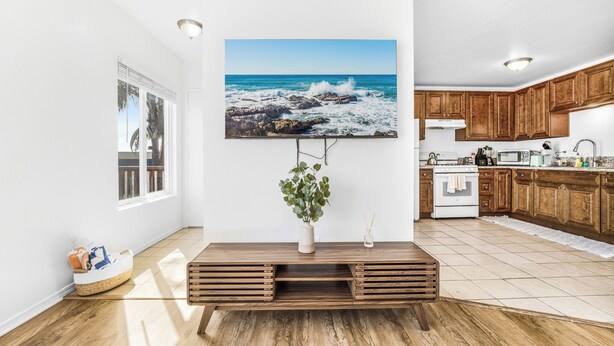 A modern kitchen with wooden cabinets, a large island, and a view of the ocean through a large window. - NEW 1br Ocean Beach Apartment w/ Parking - Short Walk to the Beach (San Diego)