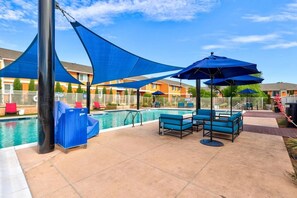 Un espace piscine agrémenté de parasols bleus, de chaises longues et d’une piscine.