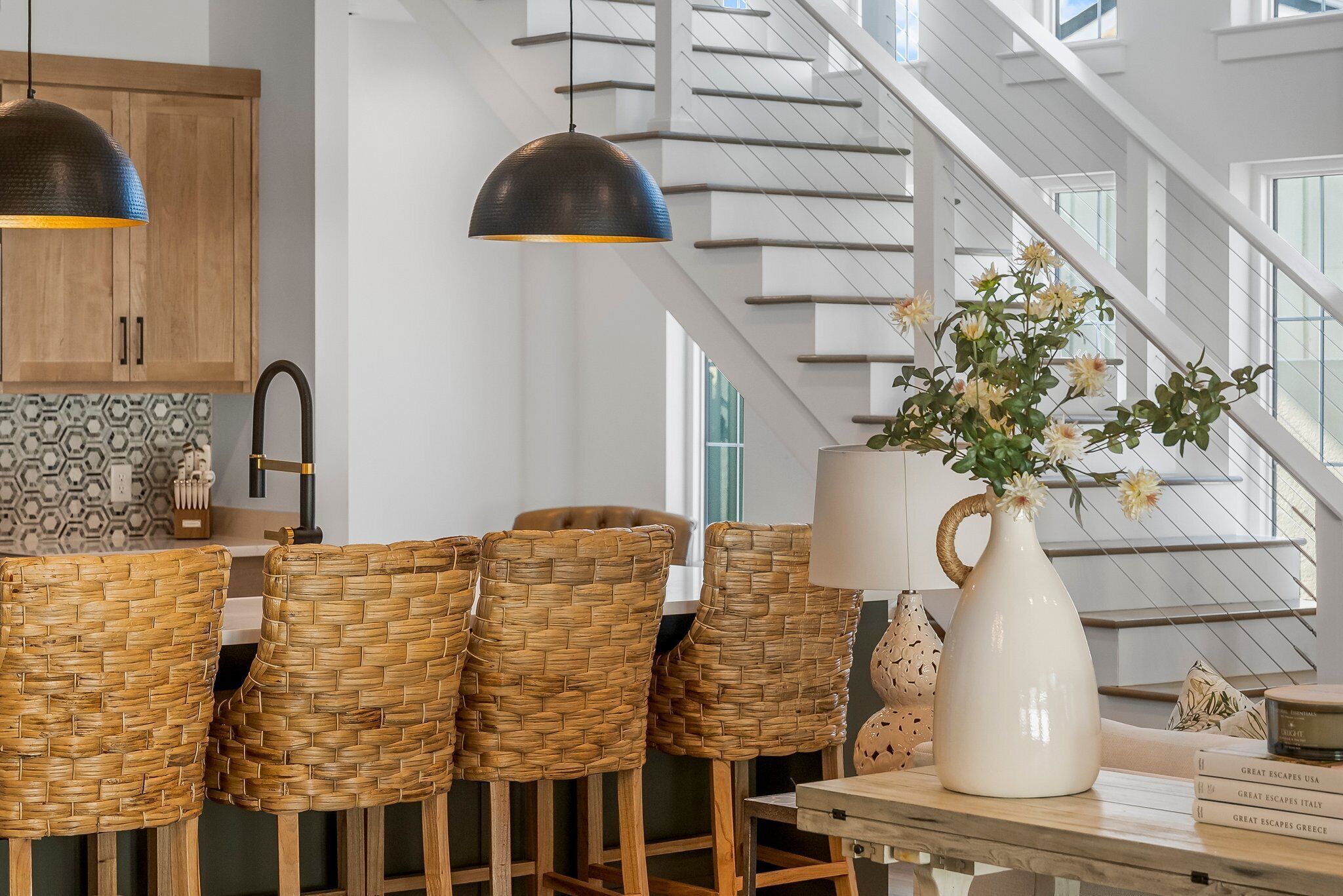Una cocina moderna con sillas de mimbre, lámparas colgantes y una escalera con vistas.