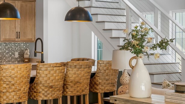 Una cucina moderna con sedie in vimini, lampade a sospensione e una scala che offre una vista panoramica.