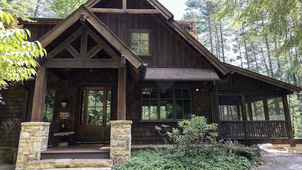 A wooden cabin with a stone foundation, large windows, and a porch. - BEAR'S DEN  - Spacious mountain home on river game room & fire pit in Burlingame (Sapphire)