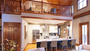 A spacious kitchen with a central island, wooden ceiling, and a dining area with wicker chairs. - BEAR'S DEN  - Spacious mountain home on river game room & fire pit in Burlingame (Sapphire)