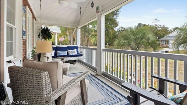 A covered porch with wicker furniture, a ceiling fan, and a view of the outdoors.