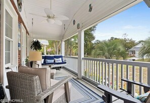 A covered porch with wicker furniture, a ceiling fan, and a view of the outdoors. - Cozy 4 Bedroom beach bungalow with private HEATED pool & golf cart. (Oak Island)