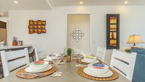 Un coin repas avec une table mise pour le repas, des chaises et des œuvres d’art murales.