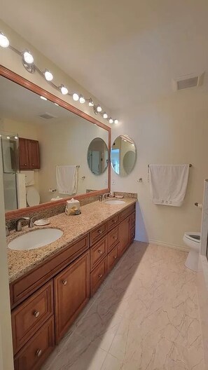 A bathroom with two sinks, wooden cabinets, a large mirror, and a towel rack.