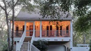 A two-story house with a covered porch and a garage. - 5 mins to beach, golf cart & fenced in yard. Pet-friendly! (Oak Island)