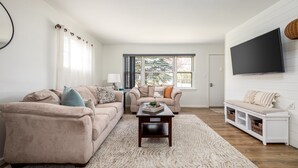Ein Wohnzimmer mit einem beigen Sofa, einem Holztisch und einer weißen Bank.