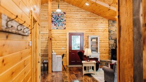 L’intérieur chaleureux d’un chalet en bois, avec un plancher en bois, une porte rouge, une cheminée et une pancarte accueillante.