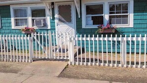 A house with a white picket fence, a front door, and two windows with flower boxes. - Ocean Beach, Fire Island,NY 4 bed,2 Bath, Sleeps 9, Full Kitchen, Deck, Bicycles (Ocean Beach)